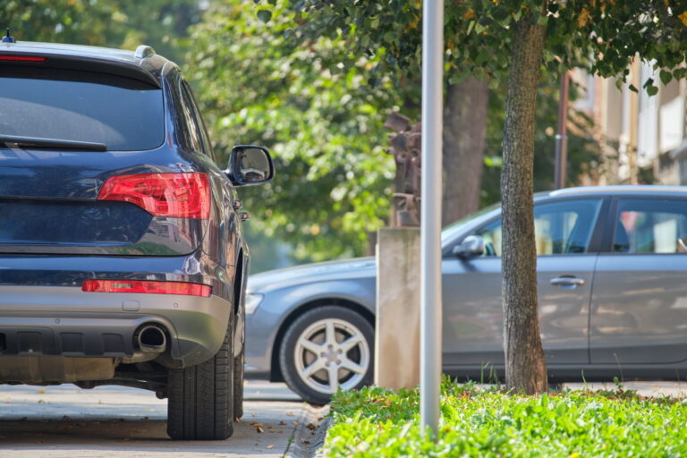 City traffic with cars parked in line on street side.