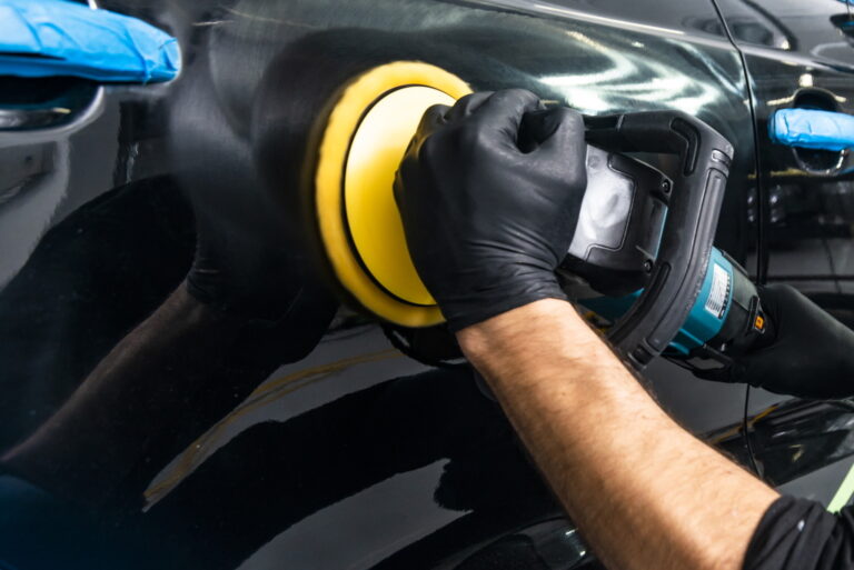 Car polish wax worker hands applying protective tape before polishing. Buffing and polishing car. Car detailing. Man holds a polisher in the hand and polishes the car. Tools for polishing